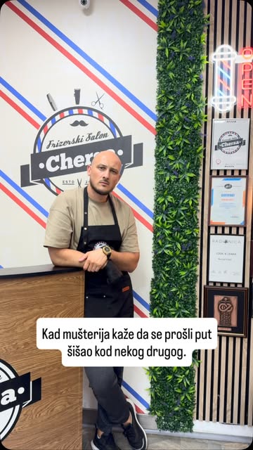 Mersad Fazlić naslonjen na zid salona sa prugama i logotipom Chersa